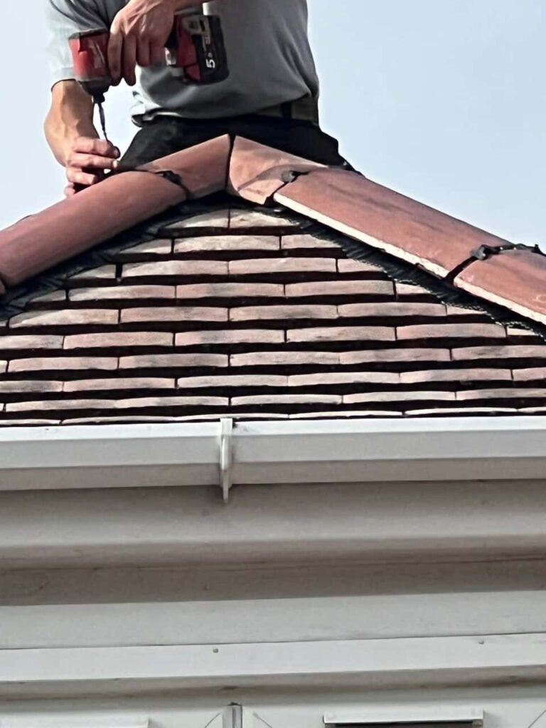 This is a photo of one of the operatives of Burwell Roofing Repairs installing new ridge tiles